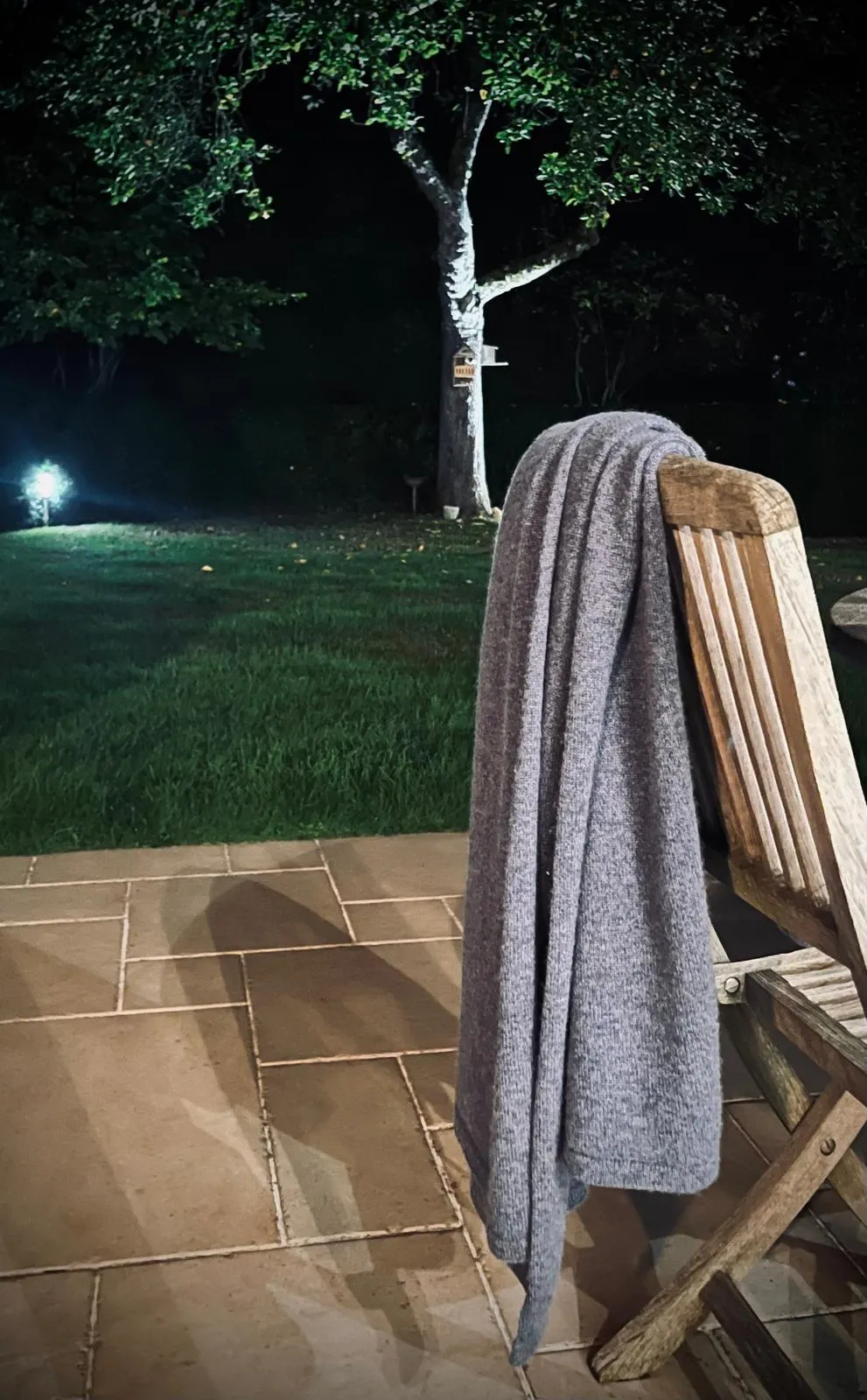 Un plaid Ekhnii posé sur une chaise de jardin, le soir