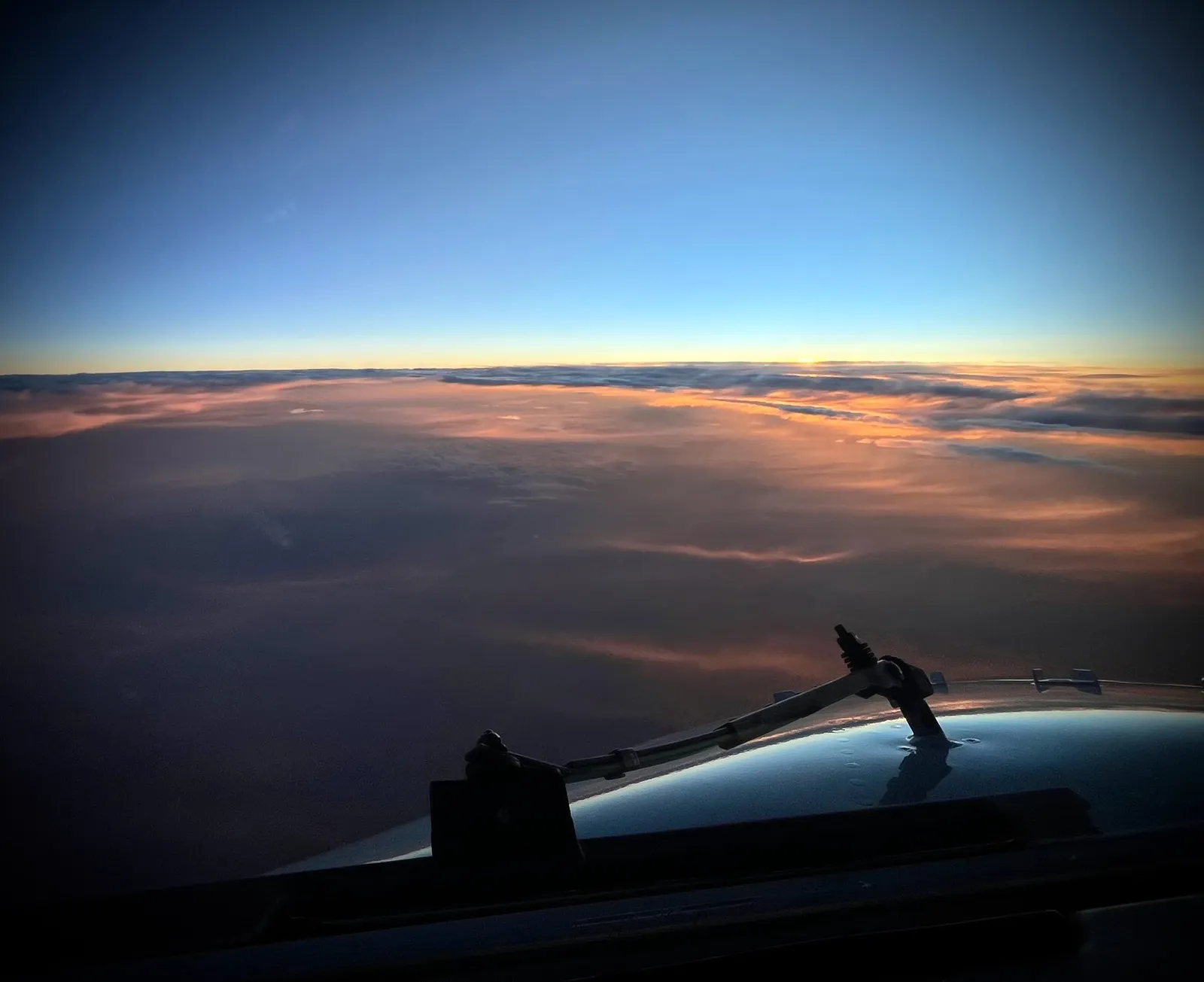 Vue du cockpit au-dessus des nuages, au coucher du soleil